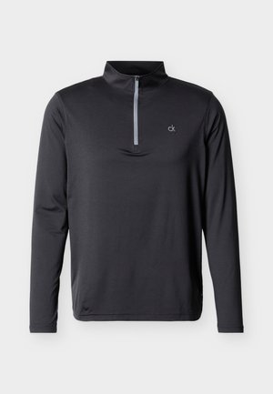 Zwarte pullover met lange mouwen en een korte grijze ritssluiting bij de hals, met een klein wit "ck"-logo op de borst.