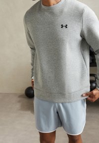 Gray sweatshirt with round neckline and black logo, paired with light blue shorts featuring white trim. Smooth fabric, relaxed fit.