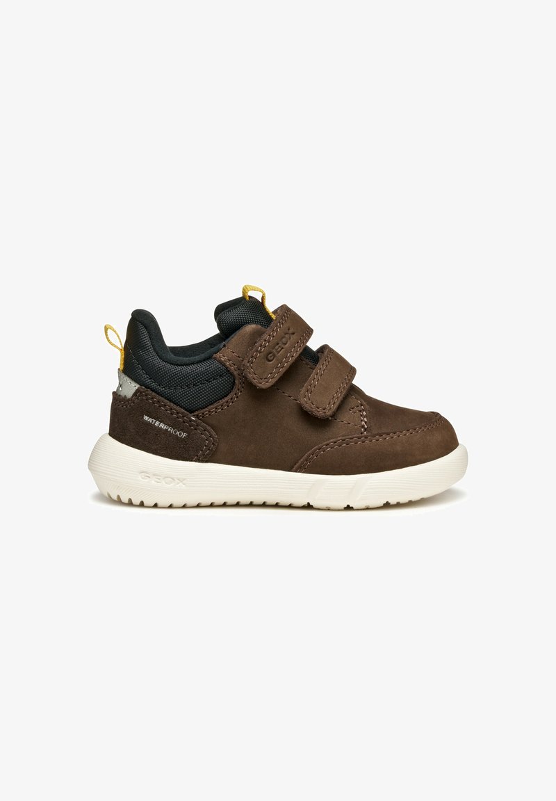 Chaussure marron imperméable pour tout-petit avec col rembourré noir, deux bandes velcro, languettes jaunes et semelle blanche, vue de côté.