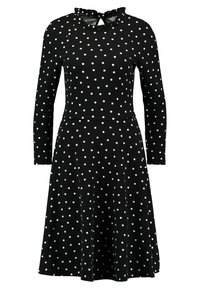 Musta mekko, jossa on pitkät hihat, valkoisia pilkkuja, röyhelökaulus ja levenevä helma. Sileä kangaspinta.