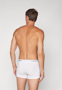 Witte katoenen boxershorts met een Calvin Klein logo-elastiek, met een gladde textuur en een aansluitend ontwerp, weergegeven vanaf de achterkant.