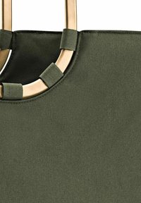 Olijfgroene draagtas met een gladde textuur, voorzien van goudkleurige hardware en gestikte accenten rondom de cirkelvormige opening.