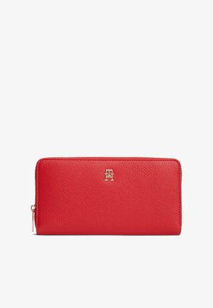 Punane nahast rahakott kruusliku tekstuuriga, esiküljel kuldse tooniga logoga ja ülevalt servast tõmblukuga sulgemisega.