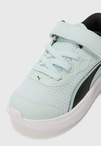 Chaussure de sport bleu clair avec dessus en mesh, accents texturés, semelle blanche et détails noirs. Comprend des lacets et une sangle à boucle crochée.