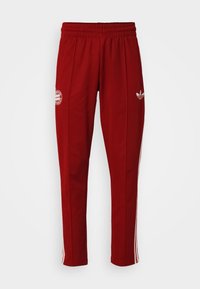 Röda träningsbyxor med dragsko i midjan, vita sidoränder och en logotyp på vänster ben, tillverkade av slät och lättviktsmaterial.