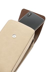 Beżowy portfel z zamszu z brązowym wnętrzem, wyposażony w zamek błyskawiczny, srebrny zatrzask oraz częściowo wsunięty smartfon.