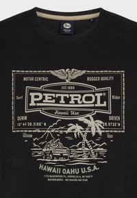 Černé tričko s bílým grafickým potiskem auta, palem a textovými prvky ve vintage designu, vyrobené z bavlněné látky.