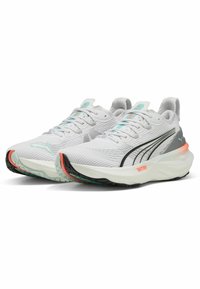 Zapatillas deportivas blancas con parte superior de malla texturada, acentos en negro y coral, cuello acolchado y suela acolchada con un patrón de relieve único.