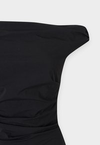 Juoda suknelė be petnešų, pasižyminti lygiu, elastingu audiniu, kūno prigludusia siluetu ir surinkimu ties liemeniu.