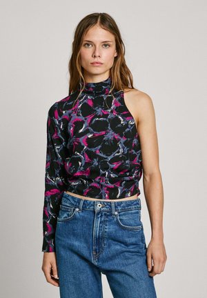 Zwarte top met bloemenprint, één lange mouw en een hoge halslijn. Voorzien van roze, blauwe en witte accenten, gecombineerd met hoogzitende blauwe spijkerbroeken.