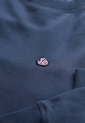 Sweat bleu marine avec col et poignets côtelés, avec un petit logo rose brodé sur la poitrine.