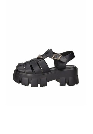 Sandalo nero con suola chunky, molte fasce larghe, fibbia regolabile sul lato e punta chiusa.