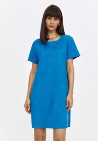 Niebieska sukienka z krótkim rękawem wykonana z miękkiego, zamszowego materiału. Ma okrągły dekolt i luźny, prosty krój.