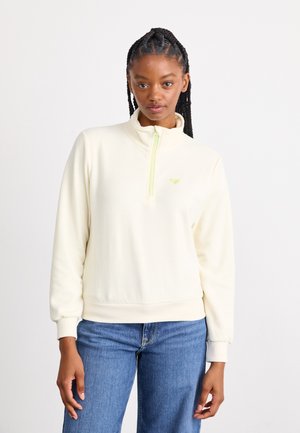 Cream fleece pullover with a high collar and half zipper in neon green. Features ribbed cuffs and waistband. Small logo on chest.