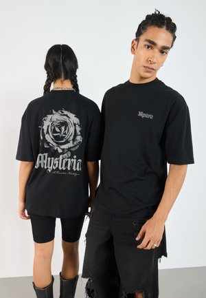 Black cotton t-shirts, one featuring a rose graphic and text on the back. The other shirt has a small logo on the front. Both have a relaxed fit.