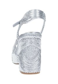 Sandalo wedge argento con una parte superiore testurizzata e scintillante, caratterizzato da un design curvo, cinturino alla caviglia e tacco a piattaforma.