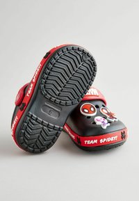 Cizme negre cu talpă din cauciuc texturat, cu accente roșii și textul "ECHIPA SPIDEY!". Include farmecuri tematice cu personaje pe față.