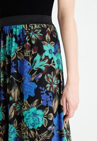 Blommig kjol med svart bakgrund, livfulla turkosa och blå blommor, samt en slät, stretchig midja.