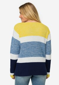 Randig tröja med blå, vit, gul och marinblå färger. Stickad struktur med en avslappnad passform och bredare halsringning för komfort.