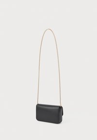 Bolso cruzado rectangular de cuero negro con cierre de solapa y fina correa de cadena dorada sobre fondo blanco.