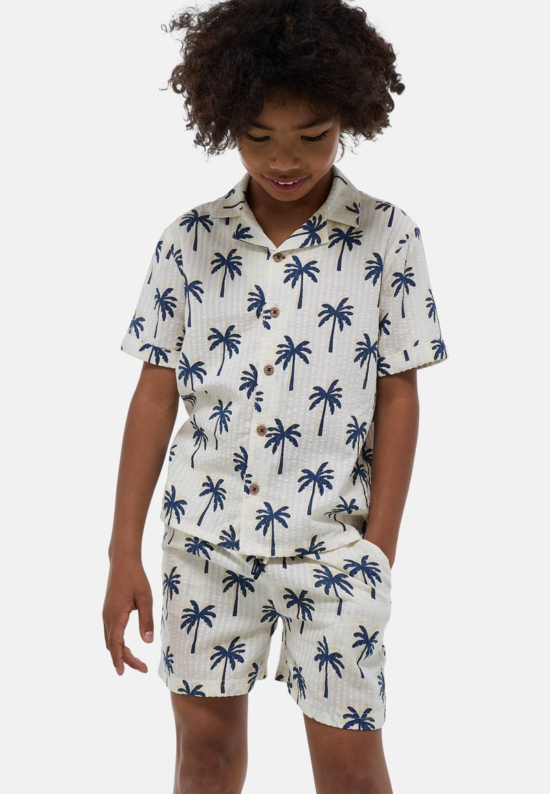 Ensemble de chemise à manches courtes et de shorts en crème clair avec un imprimé de palmiers navy ; tissu texturé ; boutons en bois ; coupe décontractée.