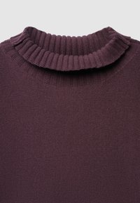 Dettaglio ravvicinato di un colletto a dolcevita a coste piegato in tessuto a maglia viola scuro che mostra la texture e i dettagli della cucitura.