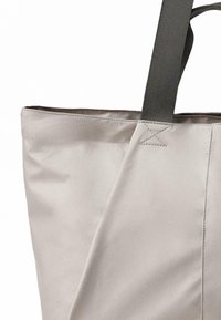 Be�žna torba s debelim crnim remenom za rame, s vidljivim šavovima i glatkom teksturom tkanine.