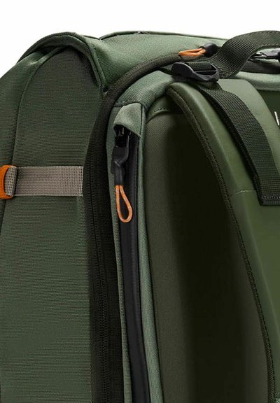 Borsa da trasporto verde in tessuto con superficie strutturata, dotata di una zip a due vie, un tirante arancione e manici in corda grigia per il trasporto.