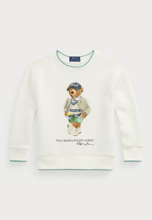 Felpa bianca con una grafica di un orso che indossa un cappellino blu, pantaloni verdi e una giacca beige. Accentuata con rifiniture turchesi al collo e ai polsini.