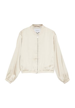 Kremowa satynowa kurtka bomberka z pełnym zamkiem z przodu, elastycznymi mankietami i elastycznym paskiem w pasie, z metką "Comma" wewnątrz kołnierza.