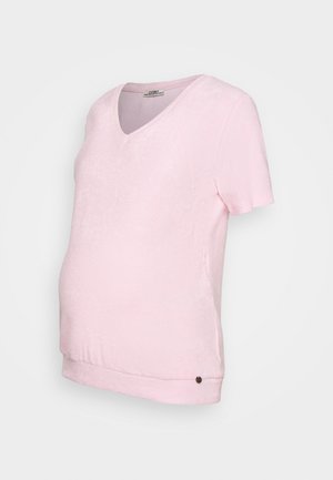 T-shirt de maternidade rosa claro com decote em V, mangas curtas e bainha curvada. O tecido tem uma textura suave, apresentando um pequeno botão de acabamento na parte inferior.