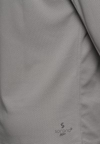 Ljusgrått tyg med ett strukturerat, bikaksmönster. Har "Sofron Agile"-märkning nära botten. Slät finish och andningsbar design.