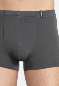 Graue Baumwoll-Boxershorts mit glatter Textur, ausgestattet mit einem markierten Bund und flachen Nähten für eine bequeme Passform.