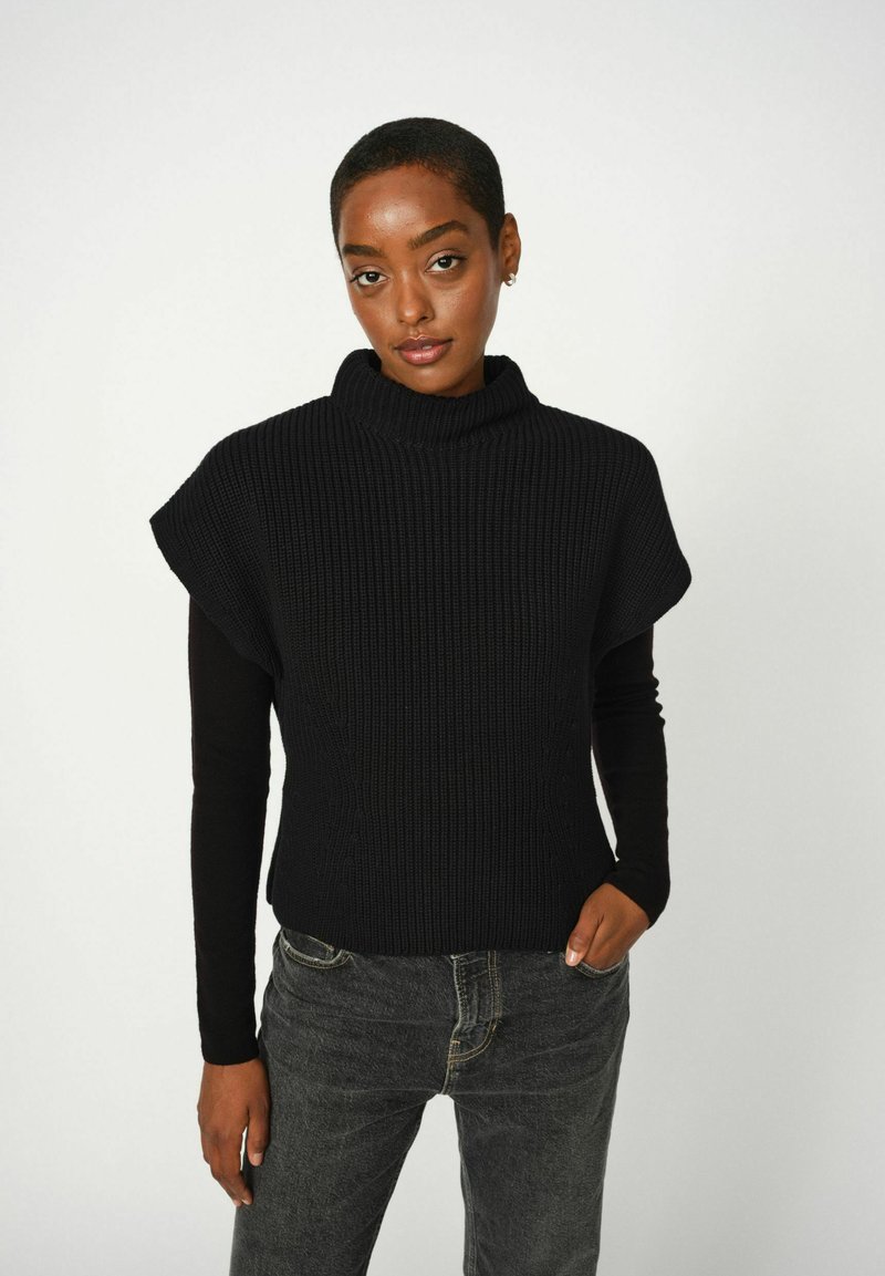 Mustmustrihe mustriga lühikeste varrukatega turtleneck-sviiter, ühendatud tumedate teksadega. Lihtne ja minimalistlik disain.