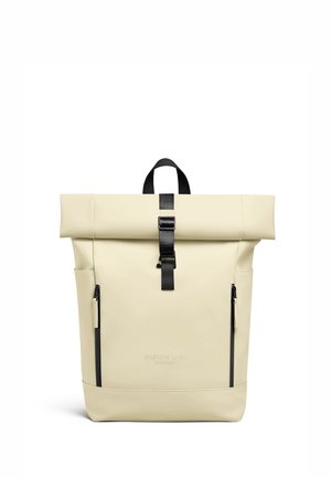 Beige rugzak met oprolbare bovenkant, zwarte gespsluiting, twee verticale ritszakken en draaghandvat, met het merk Gaston Luga Stockholm.