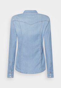 Lichtblauwe denim shirt met lange mouwen, puntige kraag en verticale naden. Voorzien van knoopsluitingen op de manchetten en een gebogen schouderstuk.