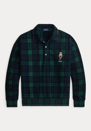 Polo à manches longues à carreaux vert foncé et bleu marine avec deux boutons blancs et un petit ours brodé portant un pull au-dessus du texte "POLO".
