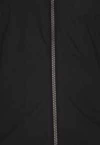 Material textil negru cu o textură netedă, cu un fermoar metalic pe mijloc, având un design cu buclă și culoare argintie contrastantă.