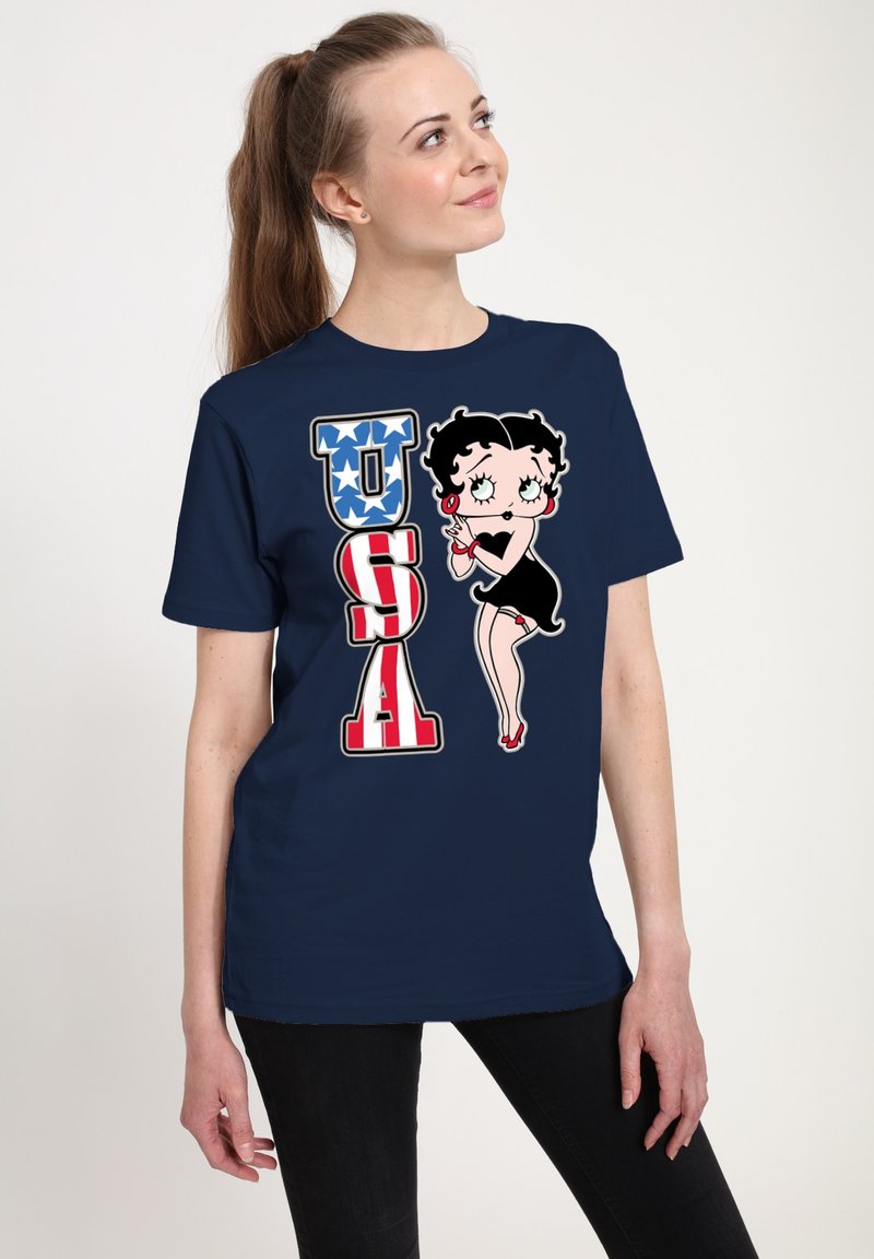 Námorně modré tričko s vintage kreslenou postavičkou "Betty Boop" vedle nápisu "USA" v tučných červených a modrých písmenech s hvězdicovými detaily.