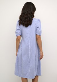 Kék és fehér csíkos ruha puffos ujjal, testhezálló felsőrésszel és bővülő szoknyával. Könnyű anyagból készült, hátul varrással.