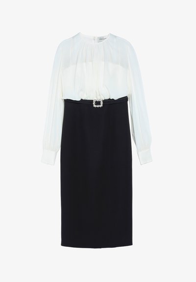 Robe à manches longues avec un haut blanc plissé, une jupe noire ajustée et une ceinture noire avec une boucle carrée en strass à la taille.