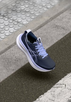 Sport shoe featuring a dark blue upper with light blue accents, textured fabric, rounded toe, and cushioned white sole.