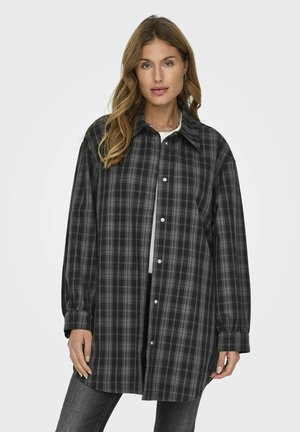 Camisa de franela de cuadros en negro y gris, de corte oversize, con cuello puntiagudo y cierre de botones en la parte delantera. Mangas largas con puños abotonados.