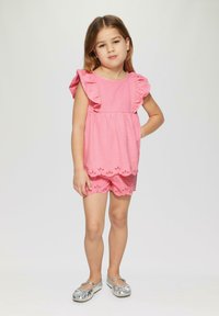 Pink textured top with ruffled sleeves, paired with matching shorts featuring scalloped hem and eyelet cutouts. Silver ballet flats.