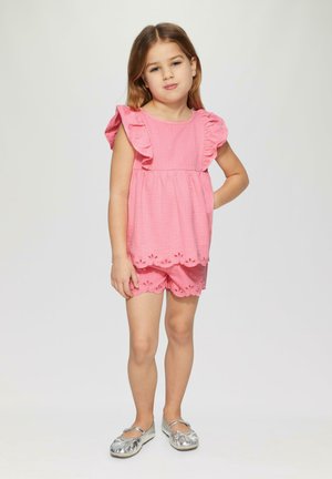 Roze getextureerde top met gerimpelde mouwen, gecombineerd met bijpassende shorts met een gekartelde zoom en oogjes uitsparingen. Zilveren ballerina's.