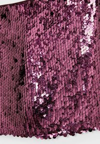 Magenta tkanina z cekinami, gęsto pokryta małymi, okrągłymi cekinami, tworzącymi błyszczącą i teksturowaną powierzchnię z różnorodnymi odbiciami światła.