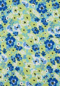 Patrón floral denso con flores azules, blancas y verdes sobre tela verde claro, con pequeños centros de flores negros y una línea de costura sutil.