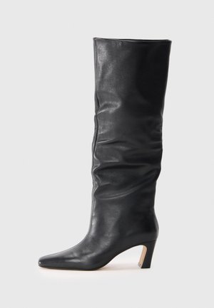 Black leather mid-calf heeled boot with a slightly slouched shaft and pointed toe on a light background.
