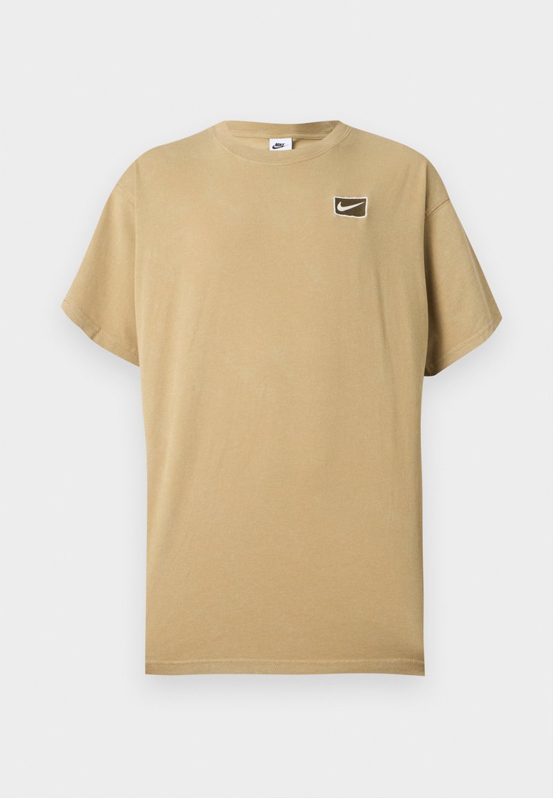 Beiges Nike T-Shirt mit kurzen Ärmeln, Rundhalsausschnitt und kleinem rechteckigem schwarzem Patch auf der linken Brust mit weißem Nike-Swoosh-Logo.