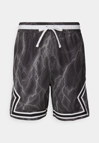 Schwarze Sportshorts mit einem Blitzmuster, aus atmungsaktivem Material, mit weißen Kordeln und gestreiften Akzenten an den Säumen.